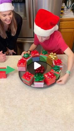 two girls in santa hats opening presents on a kitchen counter with an arrow pointing to them