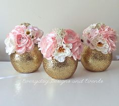 three gold vases with pink and white flowers in them