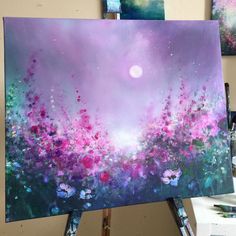 an easel is holding up a painting with purple flowers on it and the sky in the background