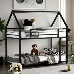 a black metal bunk bed with a teddy bear on the bottom level and white sheets underneath