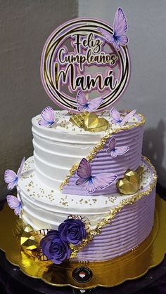 a three tiered cake with purple butterflies on the top and gold trimmings