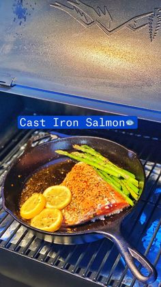 salmon and asparagus cooking on an outdoor grill with cast iron salmon pans