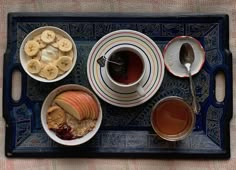 a tray topped with bowls of fruit and cups of tea