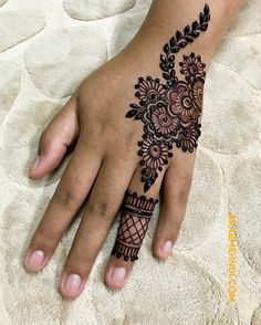 a woman's hand with henna tattoos on it and flowers in the middle