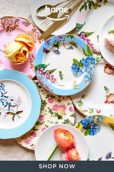 several plates with flowers on them are laid out next to forks and spoons,