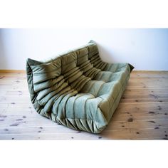 a green couch sitting on top of a wooden floor next to a wall and hardwood floors