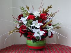 a green vase filled with red and white flowers