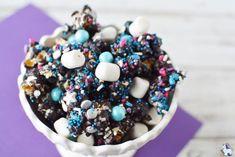 a white bowl filled with lots of sprinkles and candies on top of a purple napkin