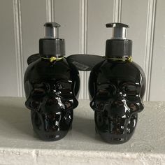 two black skull shaped soap dispensers sitting on top of a white counter