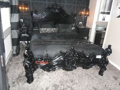 a bedroom with black furniture and carpeted flooring is pictured in this image, the bed has an ornate headboard and foot board