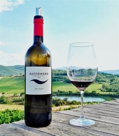 a bottle of wine sitting on top of a wooden table next to a glass of wine