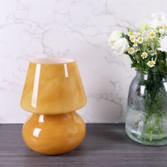 two vases with white flowers in them on a table next to a marble wall