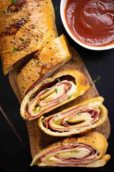 several sandwiches cut in half on a cutting board with sauces and condiments