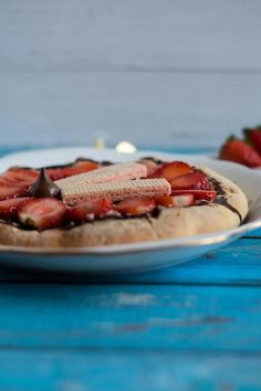 a desert with chocolate and strawberries on it sitting on a blue table next to some strawberries