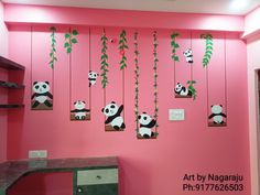 there is a pink wall with pandas hanging from it's sides and plants on the walls