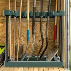 there are many different tools in the storage compartment on this shed's wall, including shovels and rakes