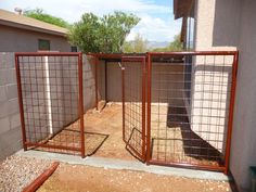 a fenced in area with two gates and a trash can on the ground next to it