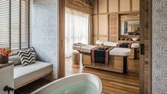 a spa room with wooden floors and white bathtub in the center, along with two massage tables on either side