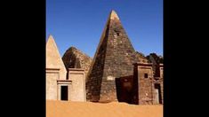 some very tall buildings in the desert with no people around them and one building is made out of stone