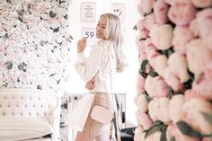 a woman standing in front of a floral wall