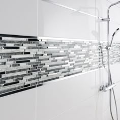 a bathroom with white and gray tiles on the shower wall next to the bathtub