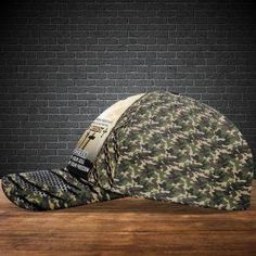 a camo hat sitting on top of a wooden floor next to a brick wall