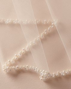 wedding veils with pearls on them are laying next to each other in the shape of a heart