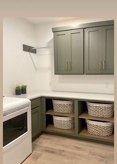 an empty laundry room with green cabinets and baskets