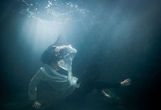 a woman in white shirt and black pants under water