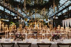 the tables are set with candles and centerpieces for an elegant wedding reception in a greenhouse