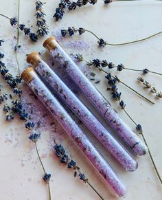 three purple marbled candles sitting on top of lavender sprigs next to each other