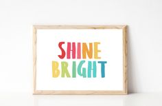 a framed print with the words shine bright in multi - colored letters on white background