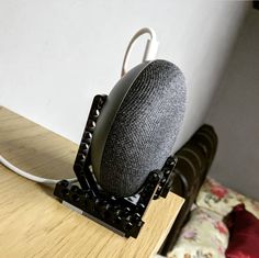 a speaker sitting on top of a wooden table next to a wall mounted phone charger