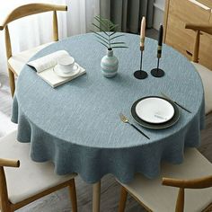 a blue table cloth with white plates and silverware sits on a dining room table