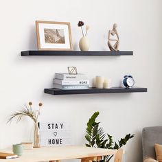 two black floating shelves above a table with books and vases on it in a living room