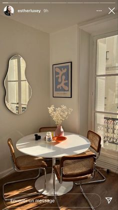 a white table with four chairs and a mirror on the wall in front of it