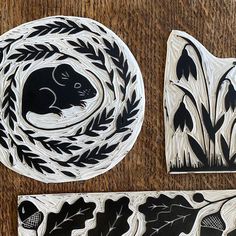 three black and white plates sitting on top of a wooden table next to each other