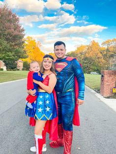 a man and woman dressed up as superman and supergirl pose for a family photo