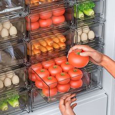 someone picking tomatoes from the refrigerator with plastic containers full of eggs and other food items