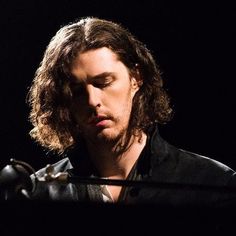 a man with long hair is playing an instrument in front of a microphone on stage