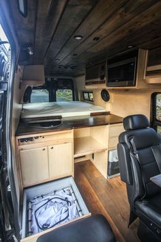 an interior view of a camper with wood paneling and black leather seats