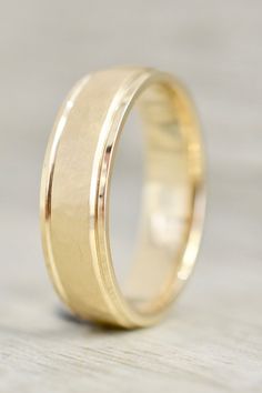 a yellow gold wedding ring on top of a wooden table