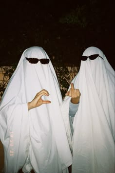 two people dressed in white are holding their hands out to each other with sunglasses on