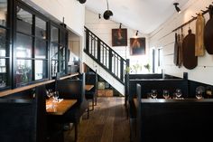 an empty restaurant with wooden tables and black chairs, framed pictures on the wall above them