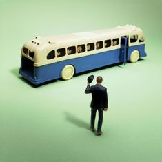 a toy man standing next to a model bus