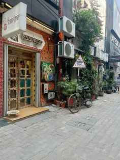 a store front with many plants on the sidewalk