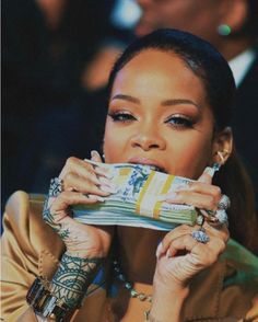 a woman with tattoos on her arm holding up a stack of money in front of her face