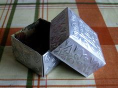 two silver boxes sitting on top of a checkered table cloth