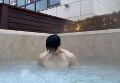 a man sitting in a hot tub with no shirt on and his head turned to the side