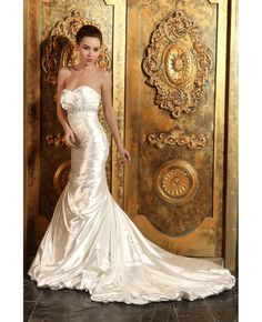 a woman in a white wedding dress standing next to a gold door with ornate carvings on it